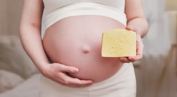 Ciężarna kobieta trzyma kawałek sera. Czy to camembert w ciąży?