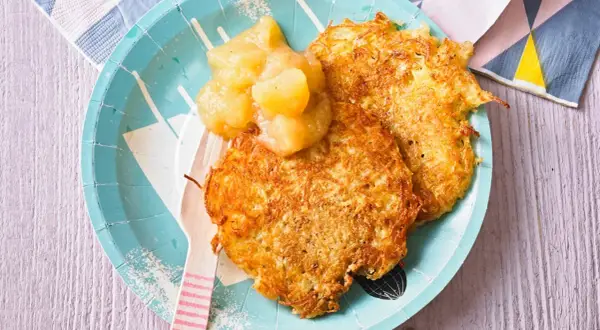 Zwei knusprige Kartoffelpuffer mit Apfelmus, ein herzhaftes Gericht, das an Omas Küche erinnert.