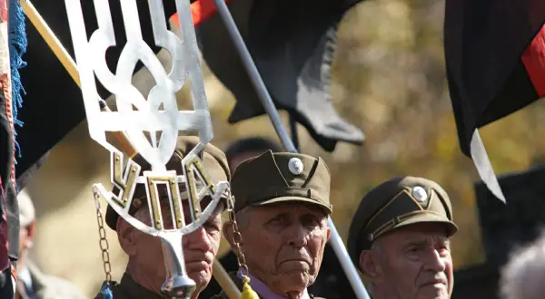 Weterani w mundurach, z symbolem Tryzub i flagami, w tym czarną z czerwonym pasem, przypominają o historii banderowców.