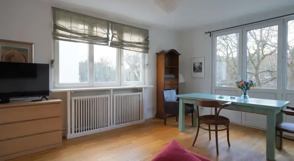 Gemütliche schlafnische im wohnzimmer mit TV, Bücherregal und Esstisch. Große Fenster lassen viel Licht herein.