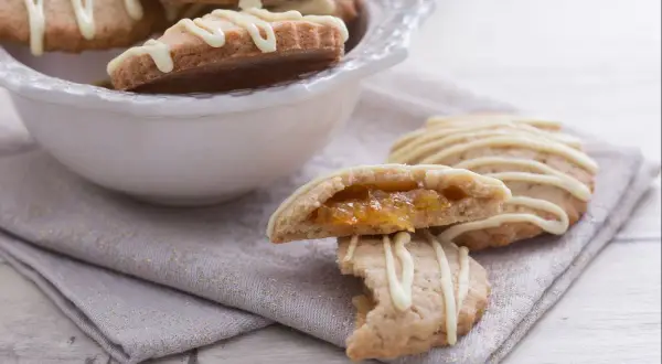 Galletas de espelta rellenas de mermelada, cubiertas con glaseado blanco.
