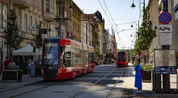 Czerwony tramwaj na ulicy w Katowicach, gdzie można podziwiać wiele atrakcji. Słoneczny dzień zachęca do spacerów.