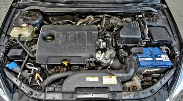Silnik Kia Ceed 1.6 CRDi. Widoczny jest czarny plastikowy kolektor, akumulator Bosch i zbiornik płynu chłodniczego.