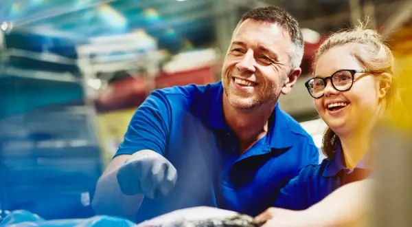 Un uomo e una donna sorridono mentre lavorano insieme. Un esempio di inclusione e pari opportunità, anche per le ferie categorie protette.