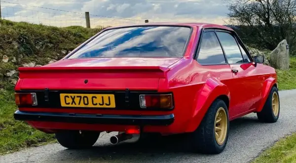 Röd Ford Escort MK2 med breddade skärmar och gul registreringsskylt.