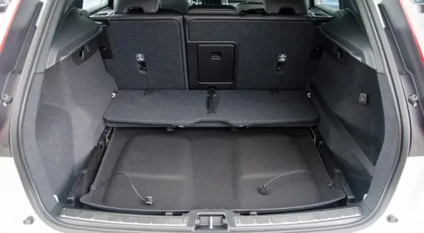 Pusta przestrzeń bagażowa Volvo XC60. Widoczne składane siedzenia i podłoga bagażnika, co pozwala ocenić jego wymiary.