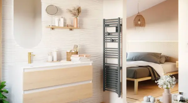 Salle de bain moderne avec meuble vasque, miroir ovale et sèche serviette gris. La puissance du sèche serviette assure des serviettes chaudes.