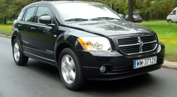 Czarny Dodge Caliber w ruchu, na mokrej drodze. Wiele osób szuka dodge caliber opinie, ten samochód wygląda na solidny.