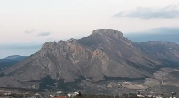 Majestuosa sierra de la Muela con sus picos rocosos y un pequeño pueblo a sus pies.