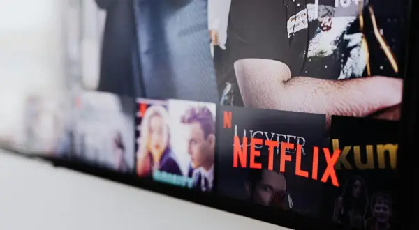 Ekran telewizora z widocznymi okładkami filmów i seriali. Widać napis "NETFLIX" i polskie nowości.