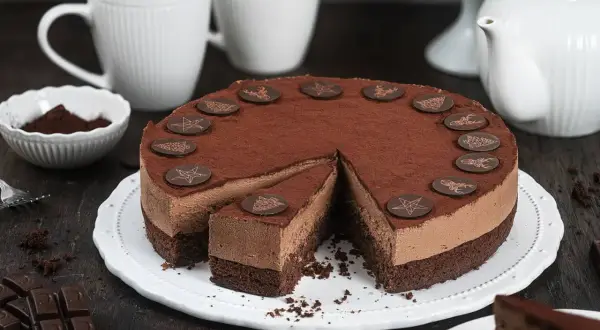 Eine köstliche Schoko Torte, bestäubt mit Kakao und verziert mit Schokoladensternen und Rentieren. Ein Stück ist bereits angeschnitten.