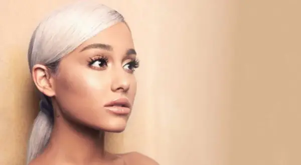 Portret Ariany Grande z blond włosami spiętymi w kucyk, patrzącej w bok.