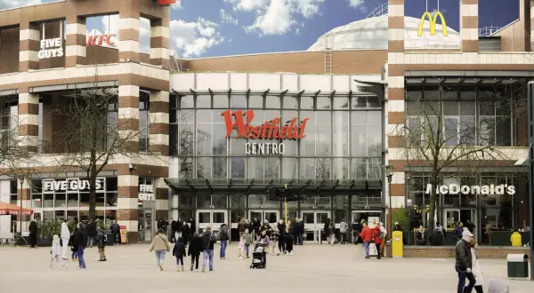 Menschen bummeln vor dem Westfield Centro, vorbei an McDonald's, KFC und Five Guys.