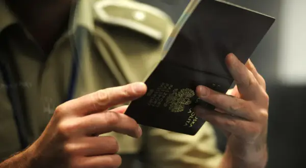 Dłonie trzymają otwarty polski paszport. Czy trzeba oddać stary paszport? Urzędnik sprawdza dokument.