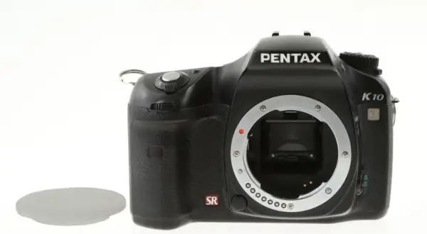 Czarny aparat Pentax K10 z widocznym mocowaniem obiektywu i osłoną. Wewnątrz widoczny jest sensor ccd.