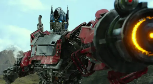 Optimus Prime, przywódca Autobotów, z niebieskimi oczami i płonącą bronią, gotowy do walki.