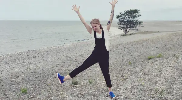 Glad tjej med armarna uppe på en stenig strand på Gotland i Sverige.