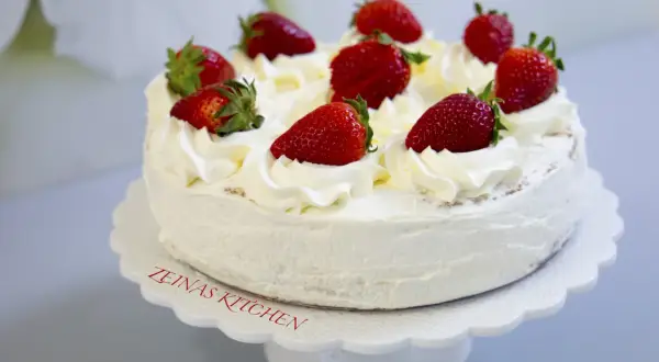 En krämig tres leches-tårta med vispgrädde och färska jordgubbar, perfekt för ett sommarfika.