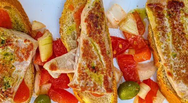 Delicioso tapeo en el ejido: tostadas con pescado a la plancha, pimientos, tomate y aceitunas.