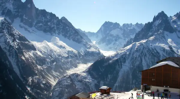 Magnifique paysage de montagne enneigée, idéal pour un week-end à Chamonix. Des skieurs profitent du soleil et des pistes.