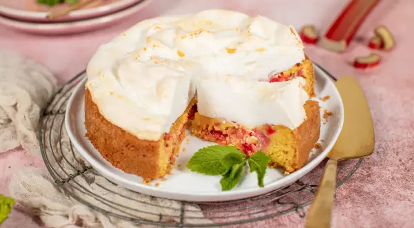 Saftiger Rhabarberkuchen mit luftigem Baiser, garniert mit frischer Minze. Ein Genuss für jeden Kaffeetisch.