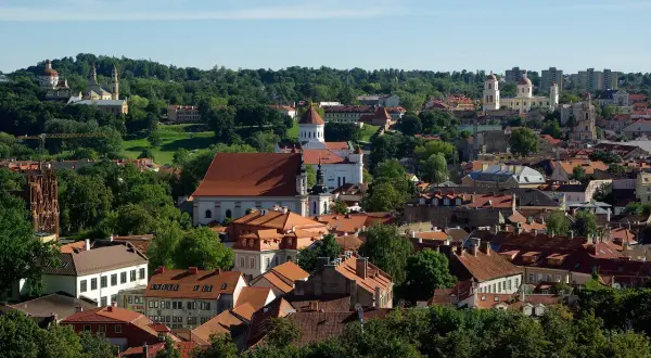 Widok na Wilno z licznymi kościołami i zielenią. Czy na Litwie jest drogo? Tutejsze zabytki i urokliwe uliczki mogą zachęcić do odwiedzin.