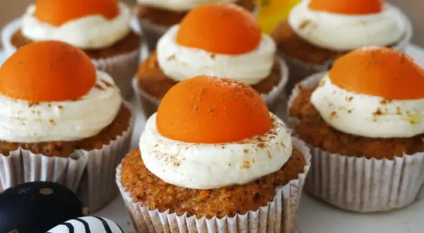 Leckere Oster Muffins mit cremiger Glasur und orangefarbener Deko.