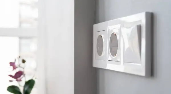Instalación eléctrica moderna: cómo poner un enchufe donde no hay. Dos tomas de corriente y un interruptor en una pared gris.