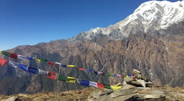 Vackra böneflaggor fladdrar i vinden under en snöklädd bergstopp. En oförglömlig upplevelse av att vandra i Nepal.