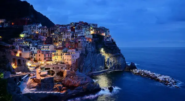 Kolorowe domy Cinque Terre, wspaniałe włochy regiony turystyczne, oświetlone nocą nad morzem.