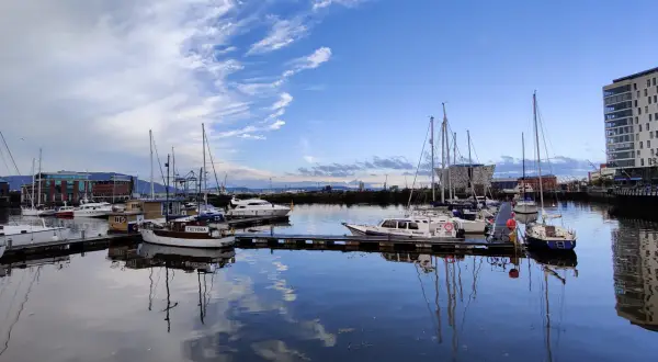 Port w Belfaście, gdzie jest? Widok na zacumowane jachty i łodzie pod błękitnym niebem z chmurami.