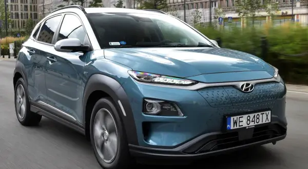 Niebieski Hyundai Kona na drodze, z widocznymi detalami, które mogą być brane pod uwagę jako **hyundai kona wady**, np. nietypowy design przedniego grilla.