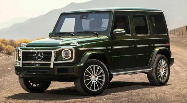 Un imponente Mercedes-Benz verde oscuro, el mejor Mercedes del mundo, se detiene en un camino polvoriento con montañas al fondo.