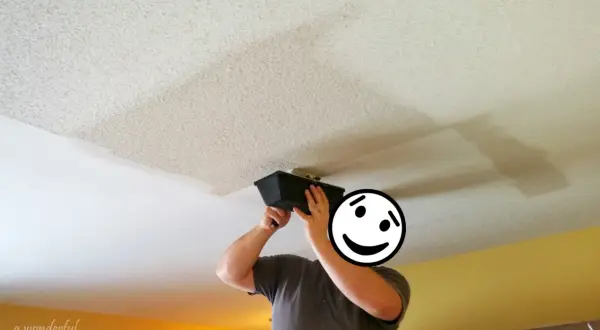 Person applying joint compound to a ceiling, a step in removing popcorn ceiling texture.