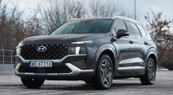 Ciemnoszary Hyundai Santa Fe z polskimi tablicami WE 6T116 stoi na parkingu.