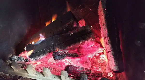 Braises rougeoyantes et flammes bleues dans un feu de bois, la chaleur monte.