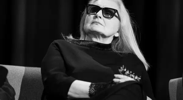 Magda Umer w okularach, z długimi blond włosami, siedzi z rękami skrzyżowanymi na piersi. Jej piosenki magdy umer alfabetycznie mogłyby być tematem tej rozmowy.