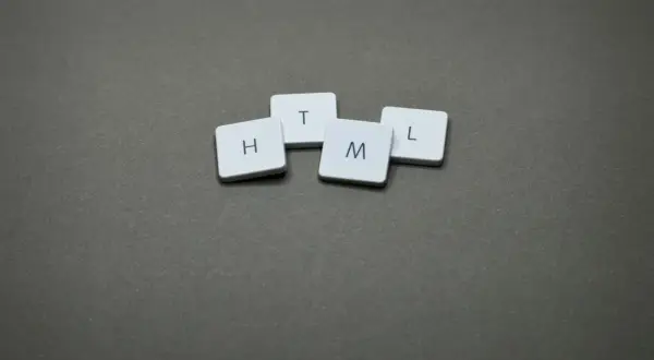 Cztery białe kafelki z literami H, T, M, L ułożone na szarym tle. Podpowiadają, jak odczytać plik HTML.
