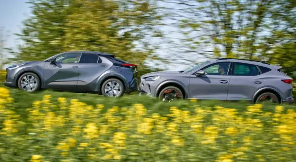 Dwa szare samochody, Toyota i Cupra, pędzą przez kwitnące pole rzepaku.