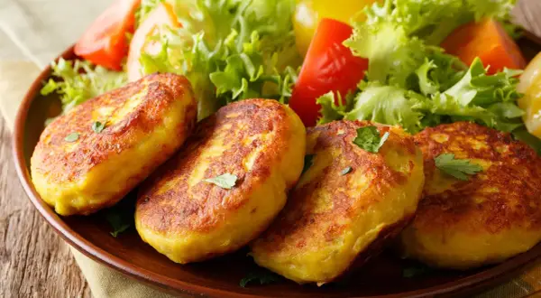 Goldbraune Kartoffelpuffer, nach Omas Kartoffelpuffer Rezept mit gekochten Kartoffeln, serviert mit frischem Salat.