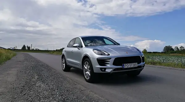 Srebrny Porsche Macan na drodze. To właśnie Porsche produkuje te luksusowe SUV-y.