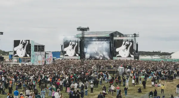 Tłum ludzi na festiwalu, wielka scena z ekranami pokazującymi gitarę. To zapewne opener 2024 lineup.