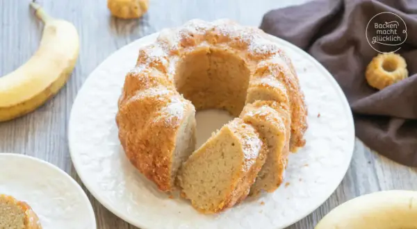 Reife Bananen verwerten: Ein saftiger Bananenkuchen mit Puderzucker bestäubt, daneben liegen frische Bananen.