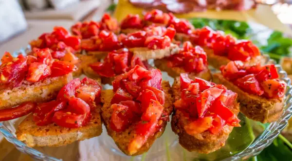 Pyszne bruschetta z pomidorami, czosnkiem i bazylią na chrupiących grzankach. Idealna przekąska na letnie przyjęcie.