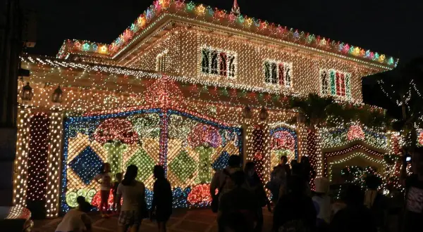 Ein Haus auf den Philippinen, das mit Tausenden von Lichtern für Weihnachten geschmückt ist. Die Fassade und der Zaun leuchten hell.