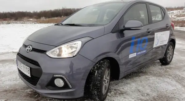 Szary Hyundai i10 na zimowych oponach, gotowy do jazdy testowej po zaśnieżonym terenie.