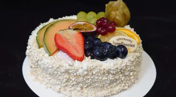 En vacker tårta, perfekt för att dekorera tårta med frukt. Toppad med melon, jordgubbar, blåbär, passionsfrukt och vindruvor.