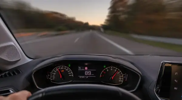 Widok z perspektywy kierowcy. Na desce rozdzielczej widać prędkościomierz wskazujący 89 km/h. To właśnie co robimy podczas jazdy samochodem.
