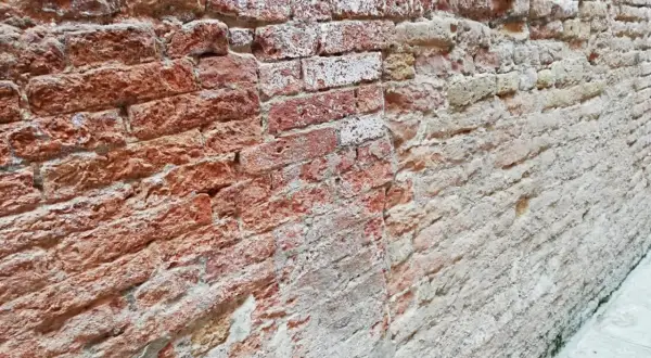 Un muro che sfarina rimedi, con mattoni rossi e bianchi consumati dal tempo, che raccontano storie antiche.