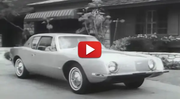 En Studebaker Avanti glider framför ett hus.
